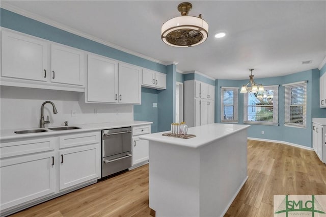 kitchen featuring crown molding, sink, an inviting chandelier, light hardwood / wood-style flooring, and white cabinets