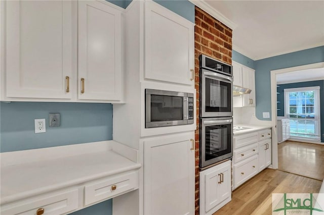 kitchen featuring stainless steel appliances, white cabinetry, ornamental molding, and light hardwood / wood-style flooring