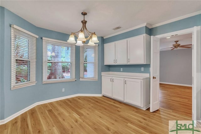 kitchen featuring white cabinets, light hardwood / wood-style floors, hanging light fixtures, and ornamental molding