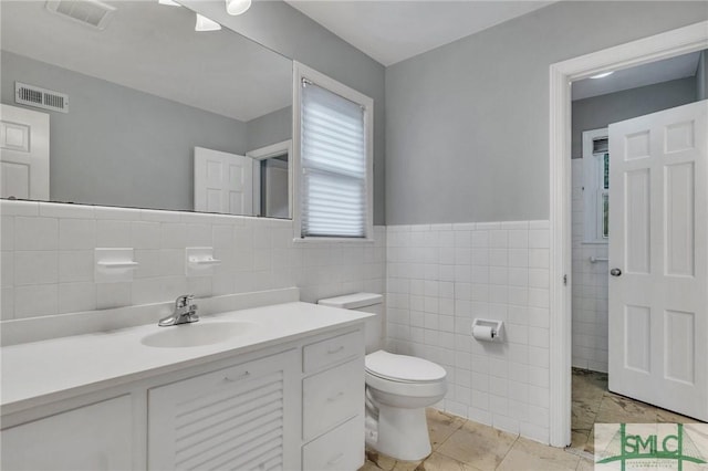 bathroom with tile patterned flooring, vanity, tile walls, and toilet