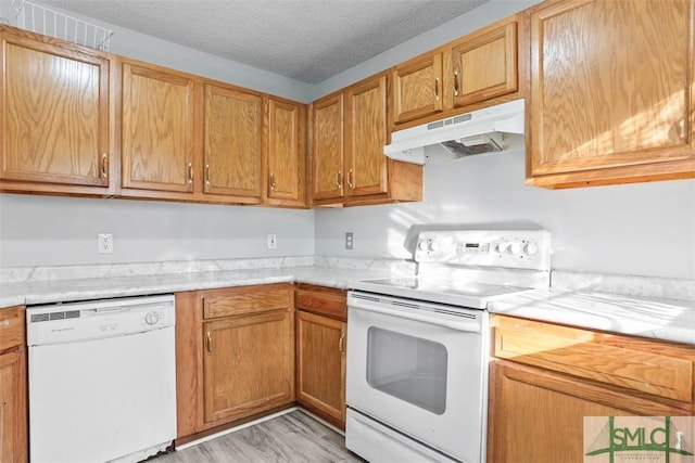 kitchen with a textured ceiling, white appliances, and light hardwood / wood-style floors