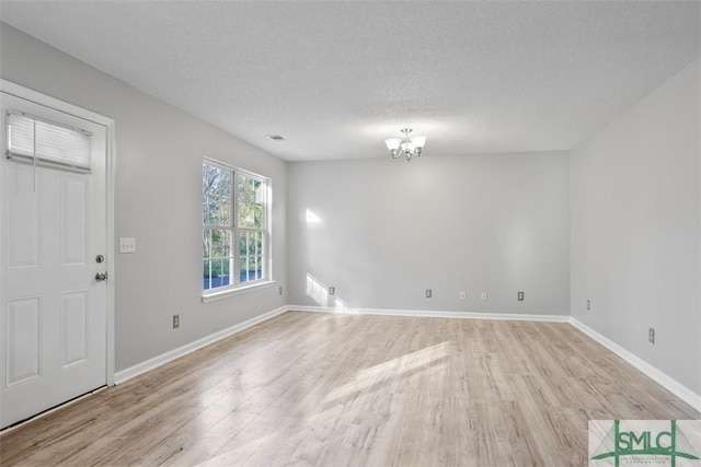 interior space with light wood-type flooring, a textured ceiling, and an inviting chandelier