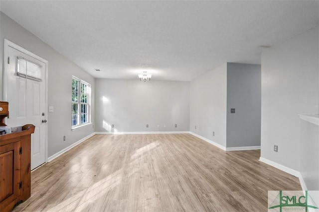 interior space with a chandelier, a textured ceiling, and light hardwood / wood-style flooring