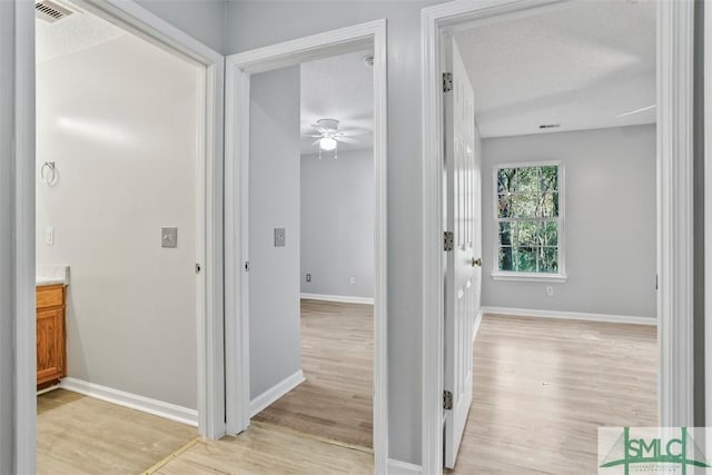 corridor featuring a textured ceiling and light wood-type flooring