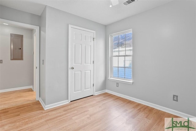 unfurnished bedroom featuring electric panel, light hardwood / wood-style flooring, and ceiling fan