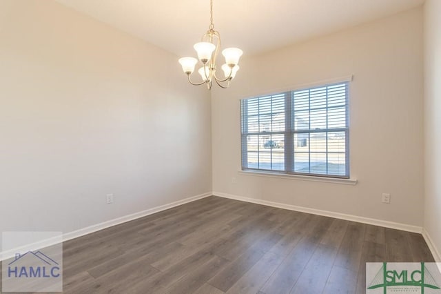 empty room with dark wood-type flooring and an inviting chandelier