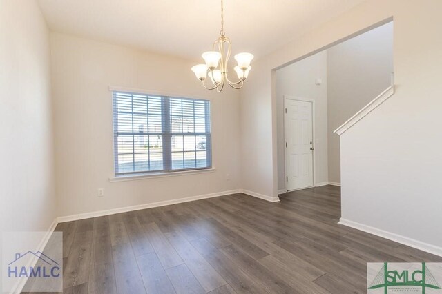 spare room featuring a notable chandelier and dark hardwood / wood-style flooring