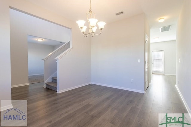 spare room with a notable chandelier and dark wood-type flooring