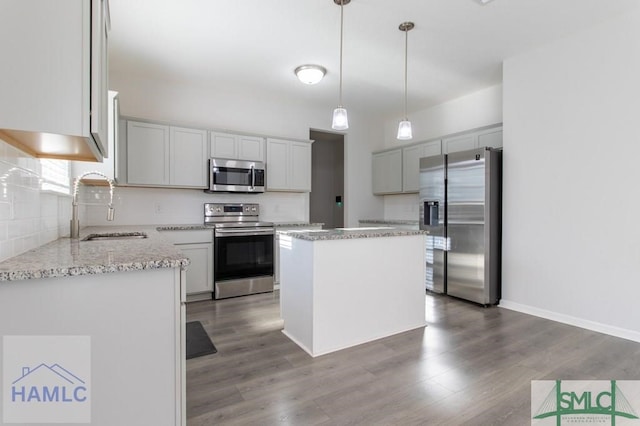 kitchen featuring hanging light fixtures, sink, a kitchen island, dark hardwood / wood-style flooring, and stainless steel appliances