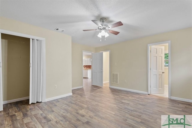 interior space featuring ceiling fan, wood-type flooring, a textured ceiling, and connected bathroom