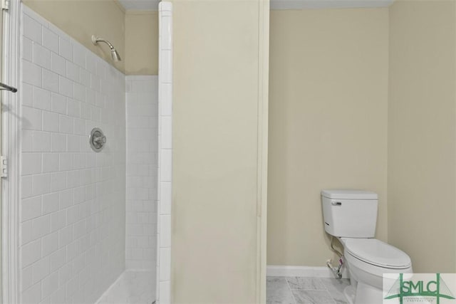 bathroom featuring tiled shower and toilet