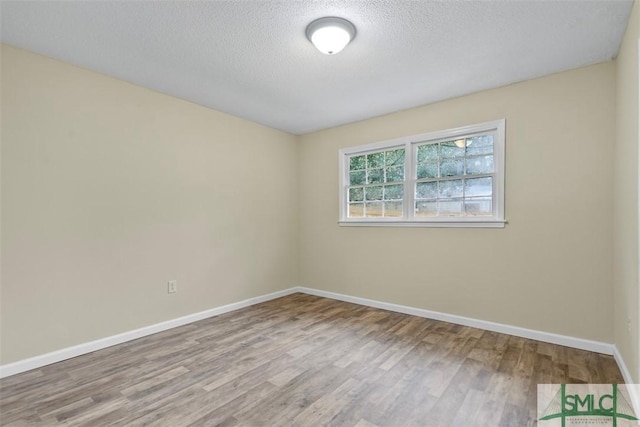 spare room with a textured ceiling and light wood-type flooring