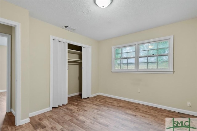 unfurnished bedroom with a closet, a textured ceiling, and light wood-type flooring