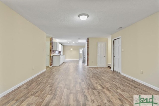 unfurnished living room with a textured ceiling and light wood-type flooring