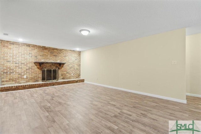 unfurnished living room featuring a brick fireplace and light hardwood / wood-style flooring