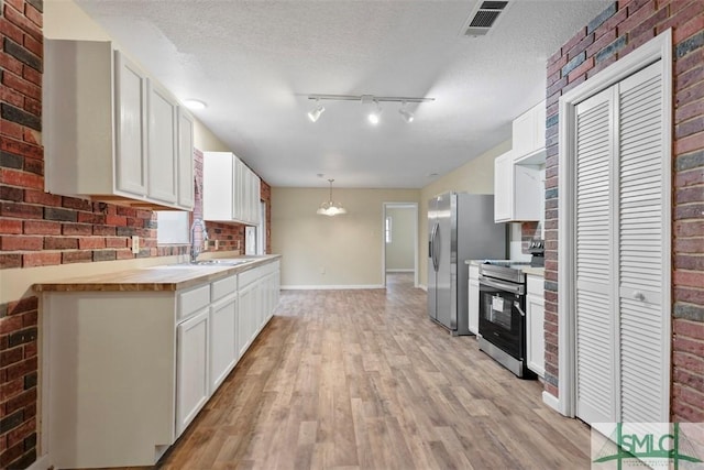 kitchen with white cabinetry, hanging light fixtures, wood counters, light hardwood / wood-style floors, and appliances with stainless steel finishes