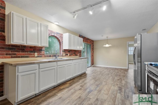 kitchen with decorative light fixtures, light hardwood / wood-style floors, white cabinetry, stainless steel appliances, and a chandelier