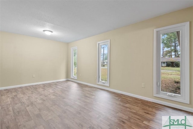 unfurnished room featuring hardwood / wood-style floors and plenty of natural light