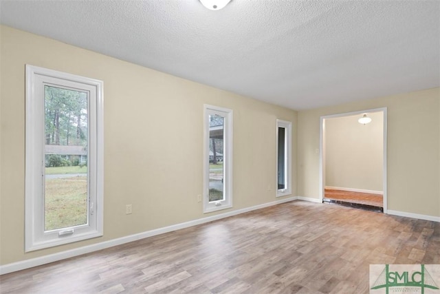 empty room featuring light wood-type flooring and a textured ceiling