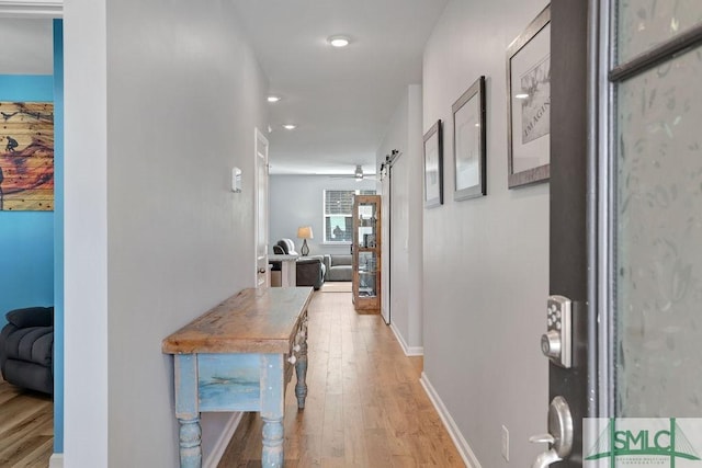 hallway with a barn door and light hardwood / wood-style flooring