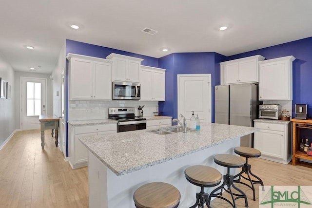 kitchen with white cabinetry, sink, stainless steel appliances, and light wood-type flooring