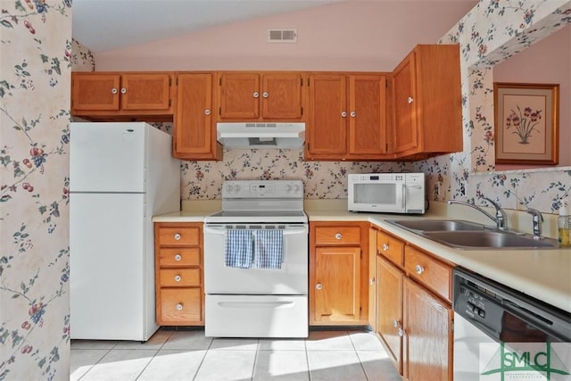 kitchen featuring lofted ceiling, sink, light tile patterned floors, and white appliances