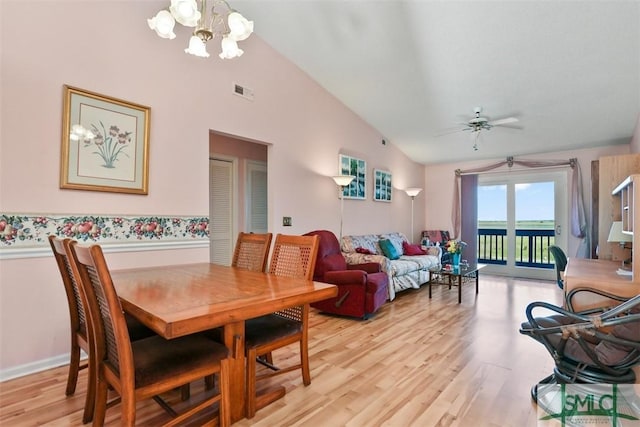 dining space with vaulted ceiling, ceiling fan with notable chandelier, and light wood-type flooring