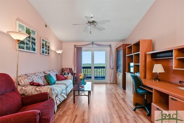 interior space with ceiling fan, vaulted ceiling, built in desk, and light hardwood / wood-style floors