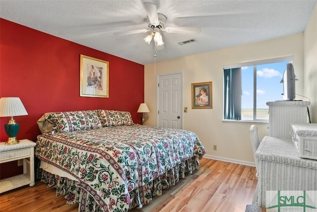 bedroom featuring ceiling fan, a textured ceiling, and light wood-type flooring