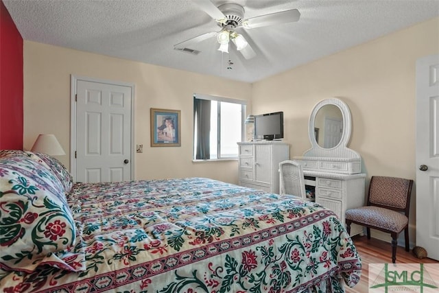 bedroom featuring ceiling fan, a textured ceiling, and light hardwood / wood-style floors