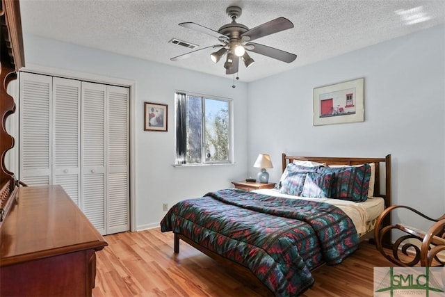 bedroom with a textured ceiling, light wood-type flooring, and a closet