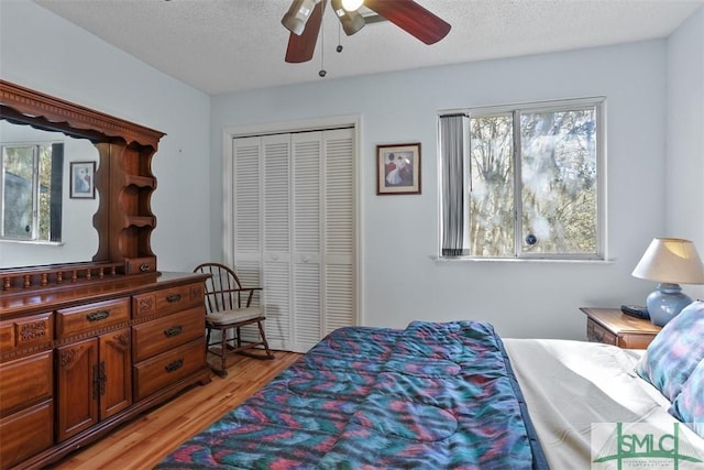 bedroom with ceiling fan, a closet, light hardwood / wood-style flooring, and a textured ceiling