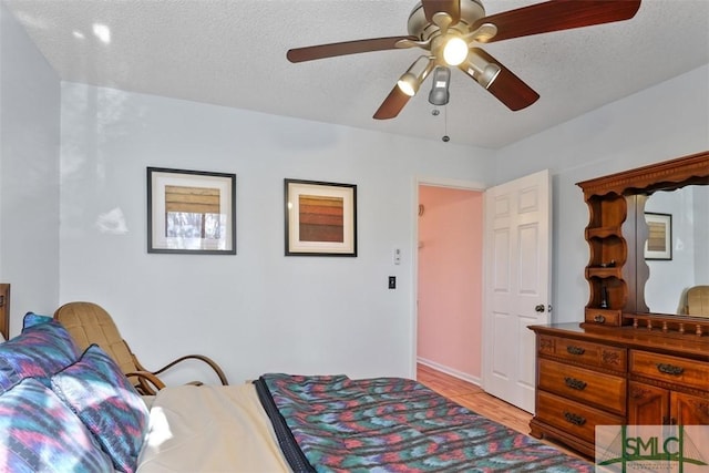 bedroom with ceiling fan, a textured ceiling, and light hardwood / wood-style floors