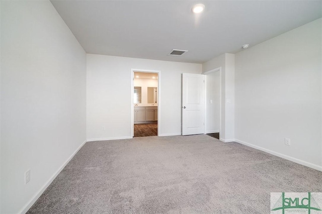 unfurnished bedroom featuring ensuite bath and carpet floors