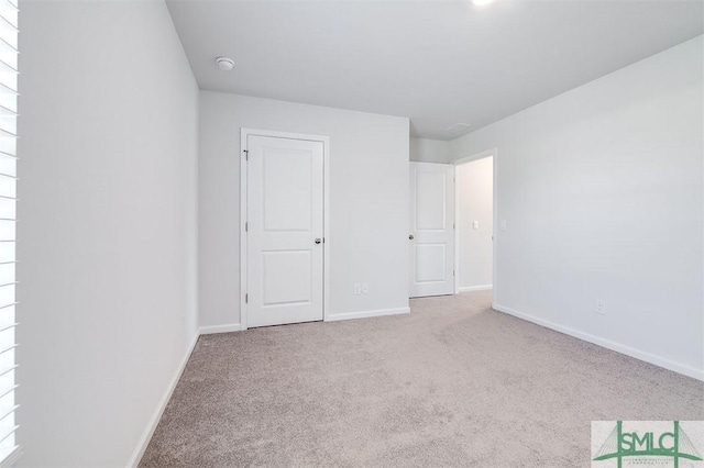 unfurnished bedroom featuring light carpet and multiple windows