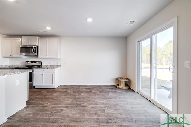 kitchen featuring light stone countertops, stainless steel appliances, white cabinetry, and light hardwood / wood-style floors