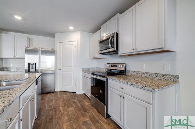 kitchen featuring white cabinets, dark hardwood / wood-style floors, light stone counters, and appliances with stainless steel finishes