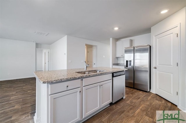 kitchen featuring sink, light stone counters, dark hardwood / wood-style floors, an island with sink, and appliances with stainless steel finishes