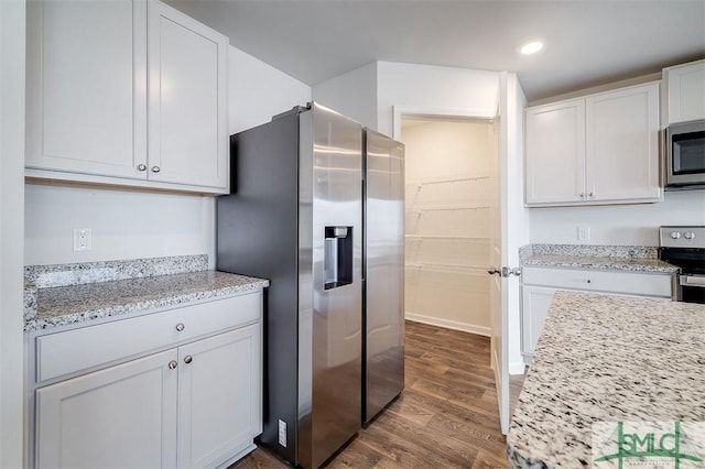 kitchen featuring light stone countertops, white cabinetry, stainless steel appliances, and dark wood-type flooring