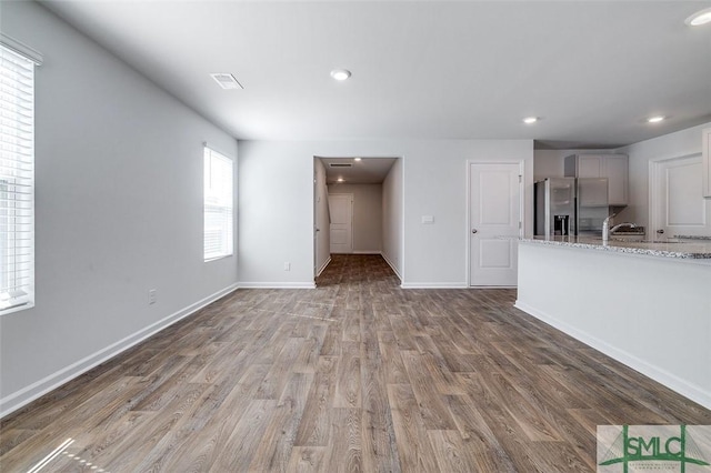 unfurnished living room with hardwood / wood-style floors, a healthy amount of sunlight, and sink