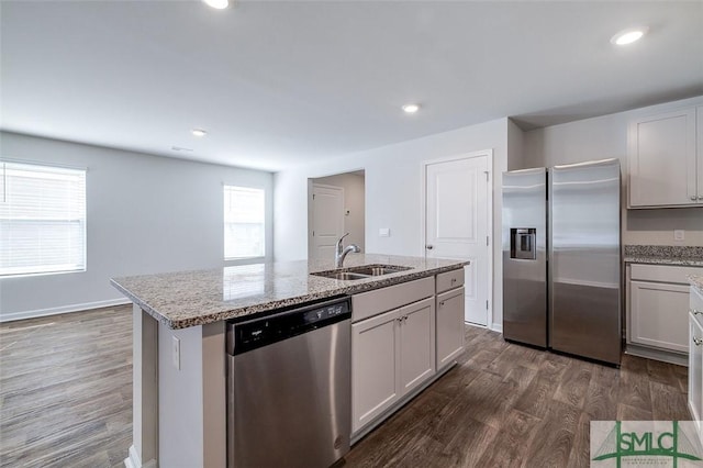 kitchen featuring white cabinetry, sink, dark wood-type flooring, stainless steel appliances, and a center island with sink