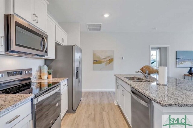 kitchen with white cabinets, sink, light hardwood / wood-style flooring, an island with sink, and stainless steel appliances