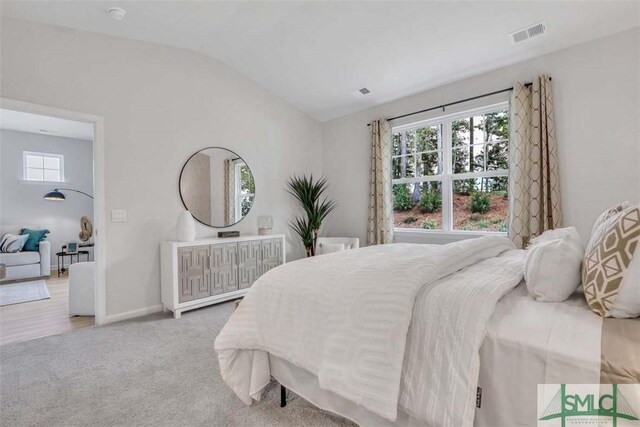 bedroom featuring light carpet and vaulted ceiling