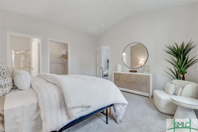 bedroom featuring a spacious closet, ensuite bathroom, lofted ceiling, a closet, and carpet