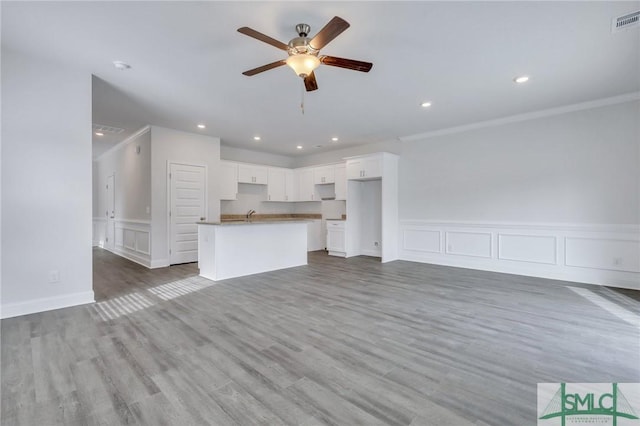 unfurnished living room with hardwood / wood-style flooring, ceiling fan, and crown molding