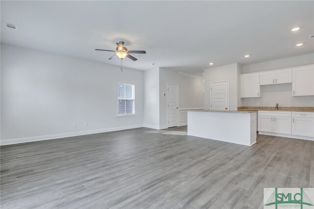 unfurnished living room featuring ceiling fan, sink, and light hardwood / wood-style flooring