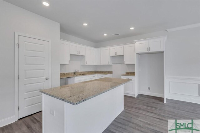 kitchen with white cabinetry, a kitchen island, and dark hardwood / wood-style floors