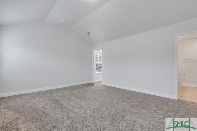 carpeted spare room with vaulted ceiling