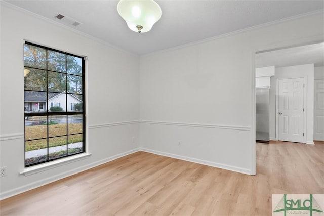 empty room with crown molding and light hardwood / wood-style flooring