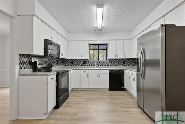 kitchen featuring white cabinets, sink, light hardwood / wood-style flooring, and black appliances